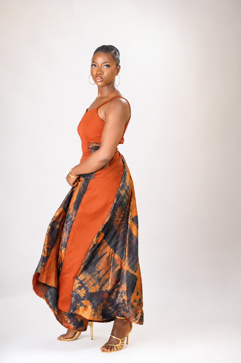 The side view of a lady wearing the Aria dress in Orange colour