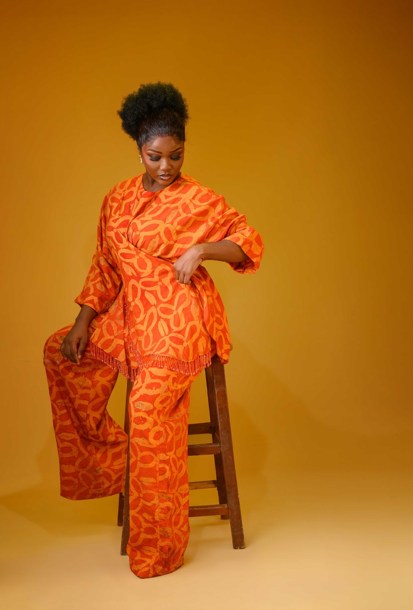 A lady wearing the Vivienne set in Orange colour sitting on a chair