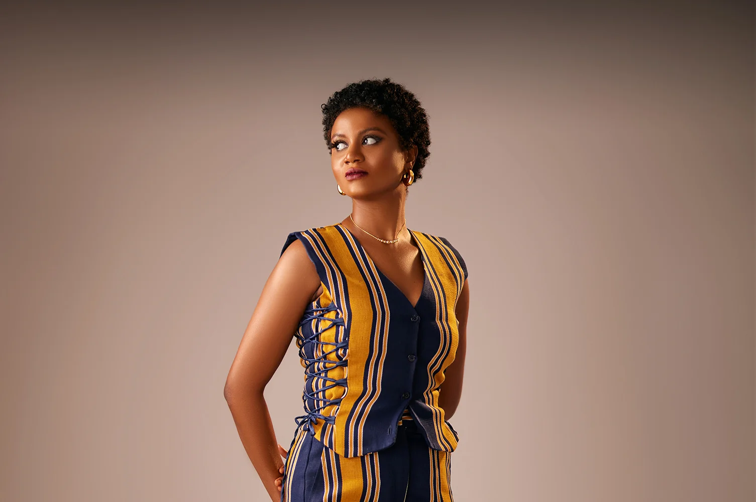 A lady wearing aso oke waistcoat and cargo pants